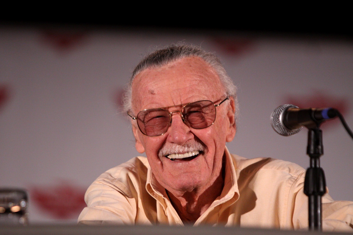 Stan Lee smiling in front of a microphone